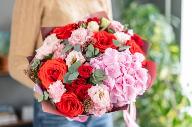 Pembe ve kırmızı renk. Kadın elinde karışık çiçek güzel buket. bir çiçekçi de çiçekçi çalışmaları. Taze kesilmiş çiçek.