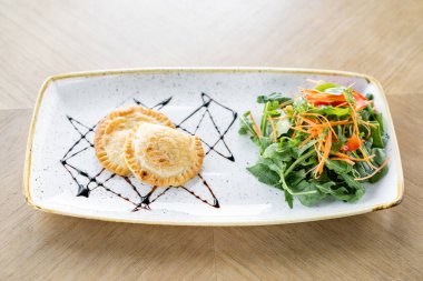 Latin Amerika kızarmış börekleri ile sebze salatası ve roka. Balzamik sosla süslenmiş. Menü Restoranı