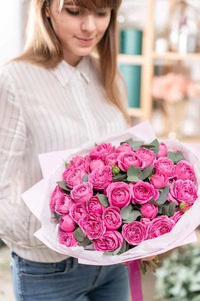 Un sacco di boccioli Rose di colore fucsia rosa. Bouquet in mano donna. il lavoro del fiorista in un negozio di fiori concetto negozio di fiori — Foto Stock