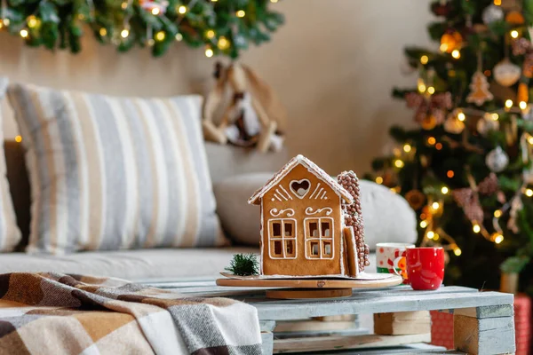 Weihnachtsmorgen im hellen Wohnzimmer. hausgemachte Lebkuchenhaus im Hintergrund Zimmer für Weihnachten dekoriert. — Stockfoto