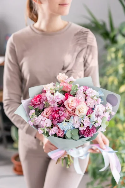 Mor ve pembe renkli. Kadınların elinde güzel bir buket karışık çiçek. Çiçekçi dükkanındaki çiçekçinin işi. Taze kesilmiş çiçek.. — Stok fotoğraf