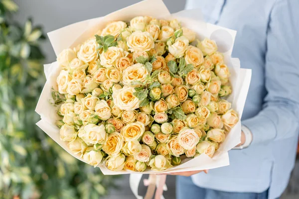 Mono bouquet of spray roses. Delicate bouquet of mixed flowers in womans hands. the work of the florist at a flower shop. Delicate Pastel color. Fresh cut flower.