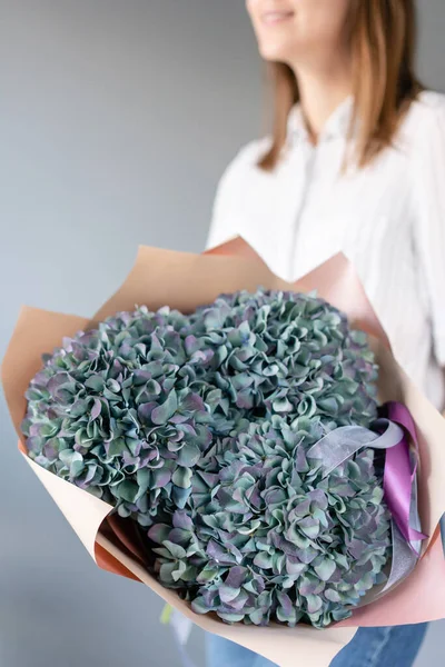 Bouquet of purple and green flower. Beautiful hydrangea flowers in womans hands. the work of the florist at a flower shop. Fresh cut flower. — Stock Photo, Image