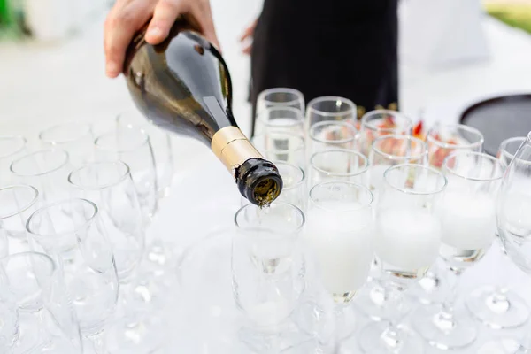 El camarero vierte el champán en las copas. Mesa llena de copas de vino blanco espumoso. Banquete en el restaurante —  Fotos de Stock