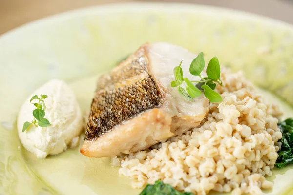 Rostad gös eller torskfisk med bulgur. Dish dekorerad med spenat. Restaurang meny — Stockfoto