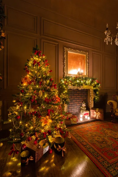 Noche de Navidad a la luz de las velas. apartamentos clásicos con chimenea, árbol decorado, sillón . — Foto de Stock