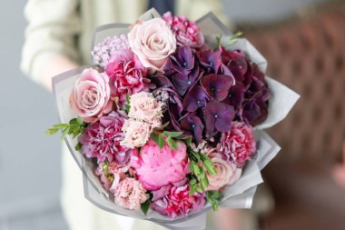 Küçük güzel buketler karışık çiçekler kadının elinde. Çiçek dükkanı konsepti. Çiçek teslimatı. Pembe şakayıklar.