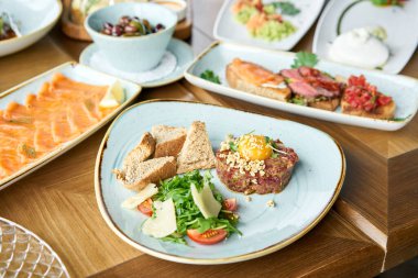 Restoranda et tartarı var. Tabakların çeşitleri masada. Masada çeşitli abur cuburlar ve antipastalar var. Restoran menüsü. İtalyan mutfağı