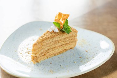 Krema ve nane yapraklarıyla süslenmiş bal süngeri pastası. Kafede kahvaltı, sabah kahvesi. Tahta masada. Restoran menüsü