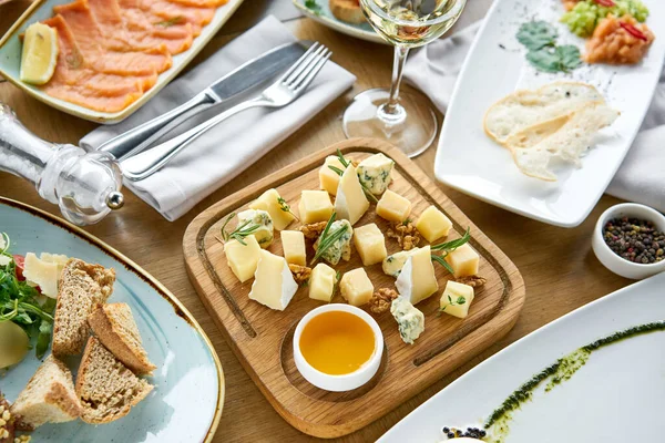 Cheese plate. Focus on delicious cheese mix with walnuts, honey on wooden table. Various snacks and antipasti on the table. Restaurant menu. — Stock Photo, Image