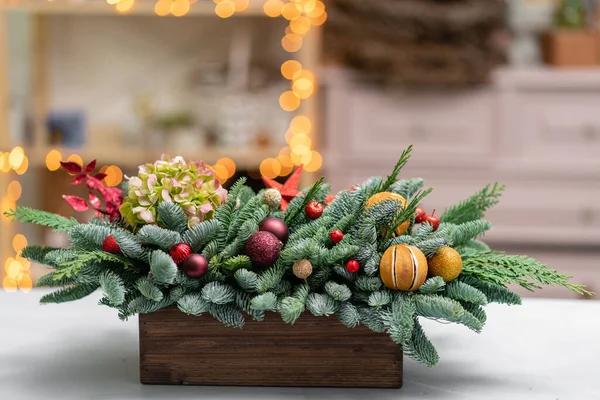 精美的节日布置，新鲜云杉与球玩具在一个乡村木箱。圣诞气氛。背景上加兰灯的Bokeh. — 图库照片