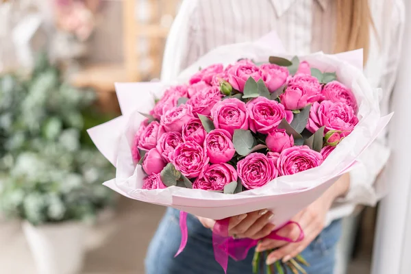 분홍색 푸크시아 색깔의 꽃봉오리를 많이 볼 수있습니다. 여자 손에 부케를 잡아. 꽃 가게에서 꽃 가게 컨셉의 꽃사는 사람의 작품 — 스톡 사진