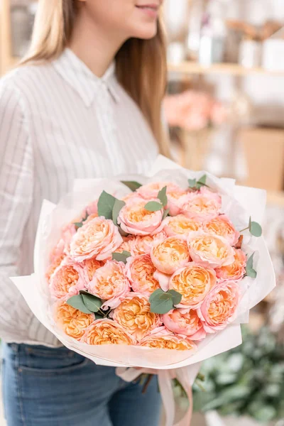 Много бутонов Розы многоцветные, пастельно-розовый и бледно-оранжевый цвет. Букет в женской руке. работа флориста в цветочном магазине Концепция цветочного магазина — стоковое фото