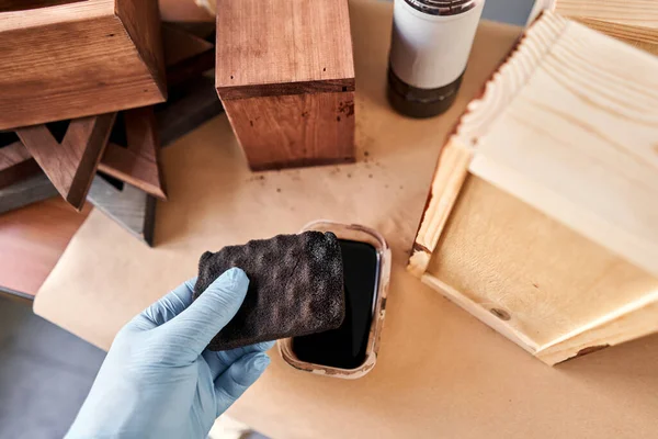 Man carpenter varnishing wooden crate for flowers with brush in her small business woodwork workshop. In your work, do you use stains or wood preservatives to show the wood pattern. — Stock Photo, Image