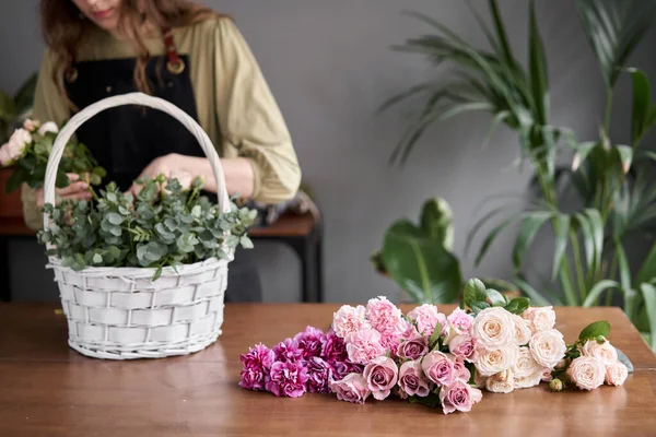 Concepto de tienda floral. Mujer florista crea arreglo floral en una canasta de mimbre. Hermoso ramo de flores mixtas. Hermoso grupo fresco. Entrega de flores . — Foto de Stock