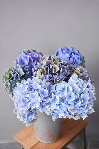 Beautiful blue hydrangea flowers in a vase on a table . Bouquet of light pink flower. Decoration of home. Wallpaper and background.