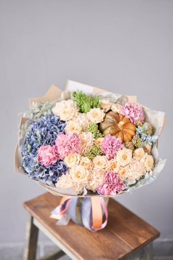 Ahşap masada bir buket karışık çiçek. Çiçekçi dükkanındaki çiçekçinin işi. Taze kesilmiş çiçek..
