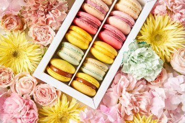 Çiçeklerin arka planında çiçekler olan bir kutuda makarna. Makarna kekleri ve farklı çiçeklerle dolu bir hayat.