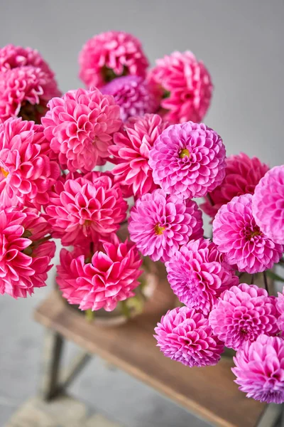 Dalias lila y rosa en jarra de vidrio, fondo de pared neutro. el trabajo de la floristería en una florería. Bonito ramo fresco. Entrega de flores —  Fotos de Stock