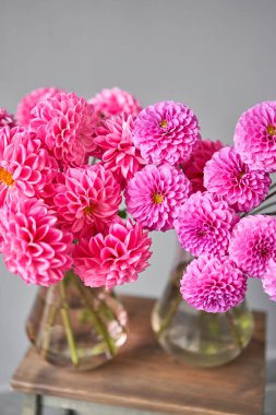 Cam sürahi içinde leylak ve pembe yıldız çiçekleri, tarafsız duvar arkaplanı. Çiçekçi dükkanındaki çiçekçinin işi. Güzel, taze bir buket. Çiçek teslimatı