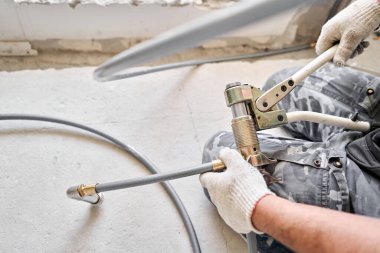 İnşaat halindeki yeni bir apartmanın beyaz radyatörüne bağlı ısıtma boruları. Su tesisatçısı olarak çalış. Beyaz duvarda su ısıtıcısı monte et.