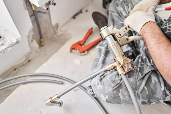 Connection heating pipes to white Radiator in a new apartment under construction. Work As A Plumber, mounting water heating radiator on the white wall indoors — Stock Photo, Image