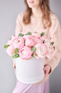 Kadınların elinde pembe şakayık buketi olan yuvarlak kutu. Katalog ya da internet mağazası için güzel şakayık çiçekleri. Çiçek dükkanı konsepti. Taze kesilmiş güzel bir buket. Çiçek teslimatı
