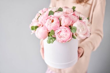 Kadınların elinde pembe şakayık buketi olan yuvarlak kutu. Katalog ya da internet mağazası için güzel şakayık çiçekleri. Çiçek dükkanı konsepti. Taze kesilmiş güzel bir buket. Çiçek teslimatı