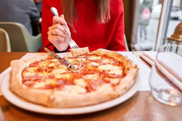 Frau isst mit Messer und Gabel eine Pizza capricciosa. Pizza mit Mozzarella-Tomaten, Artischocke, schwarzen Oliven und Basilikum Neapolitanische Pizza aus dem Holzofen. Mittagessen in einem italienischen Restaurant. — Stockfoto