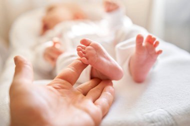 Baba, yeni doğmuş bebeğin ayaklarını tutuyor. Küçük ayaklar ebeveynlerin elinde. Ayak bakımı, yakın çekim. Mutlu aile kavramı.