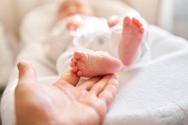 Baba, yeni doğmuş bebeğin ayaklarını tutuyor. Küçük ayaklar ebeveynlerin elinde. Ayak bakımı, yakın çekim. Mutlu aile kavramı.