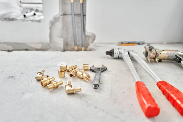 Conexión de tuberías de calefacción a radiador blanco en un nuevo apartamento en construcción. Trabaje como fontanero, montando radiador de calentamiento de agua en la pared blanca en el interior —  Fotos de Stock