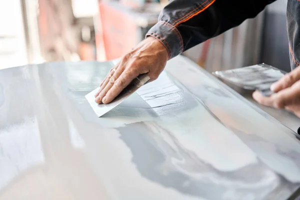 Reparerar bilkarossen, appliceringsspackel på nära håll. Mekanikern reparerar bilen. Arbeta efter olyckan genom att slipa grundfärg före målning. — Stockfoto