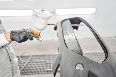 İşçi, arabanın parçalarını özel boya odasına boyuyor, kostüm ve koruyucu giysiler giyiyor. Araba servis istasyonu..