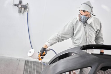 İşçi, arabanın parçalarını özel boya odasına boyuyor, kostüm ve koruyucu giysiler giyiyor. Araba servis istasyonu..