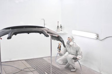 İşçi, arabanın parçalarını özel boya odasına boyuyor, kostüm ve koruyucu giysiler giyiyor. Araba servis istasyonu..