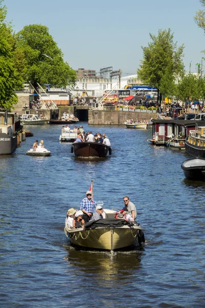 stock image AMSTERDAM, NETHERLANDS - May 6, 2018: Dutch and tourists enjoy a boat trip on the canals of Amsterdam during a beautiful spring day