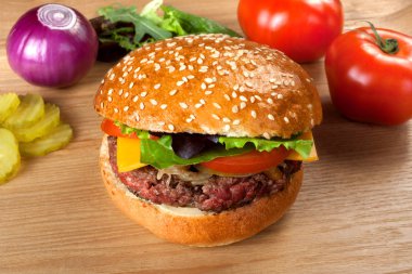 ahşap bir masa üzerinde sığır eti ile ev yapımı hamburger.
