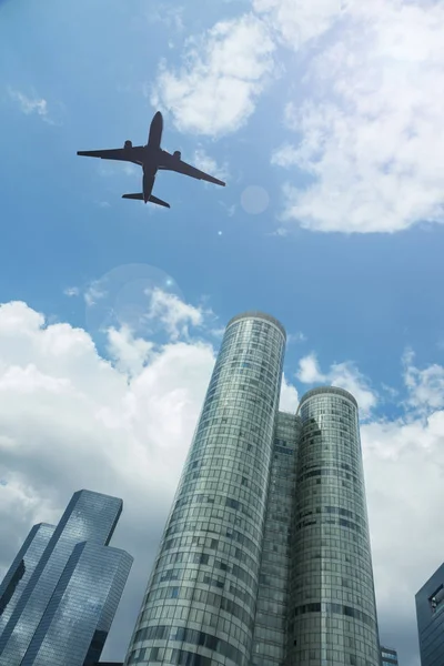 Airplane in the sky with modern buildings — Stock Photo, Image