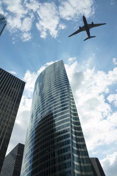 Airplane in the sky with modern buildings, with a blue sky