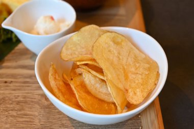 Beyaz kasede mayonez ve patates cipsi.