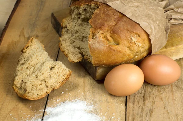 Yumurta ile ahşap bir masa üzerinde taze pişmiş ekmek