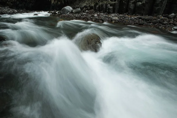 Feche o fluxo rápido de um fluxo entre rochas — Fotografia de Stock