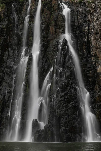 Close up entre as montanhas derrama uma alta cachoeira que derrama em um pequeno lago — Fotografia de Stock