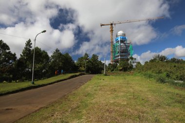 Orman ve yolun yakınında yüksek bir kule ve bir vinç inşaatı var