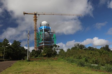 Orman ve yolun yakınında yüksek bir kule ve bir vinç inşaatı var
