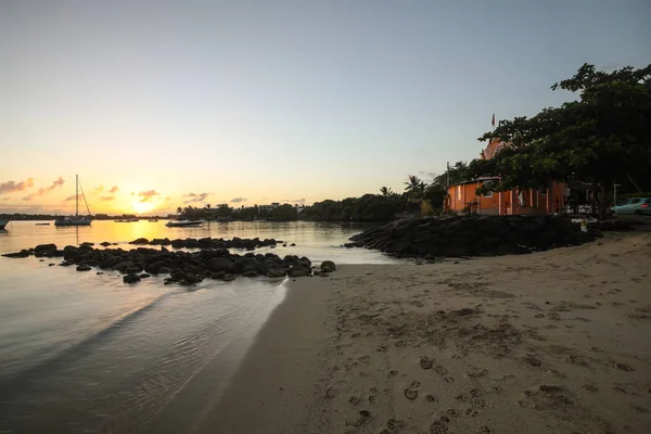 Puesta de sol en la playa de la isla de Mauricio donde los yates flotan en el agua y hay una casa — Foto de Stock