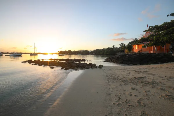 Puesta de sol en la playa de la isla de Mauricio donde los yates flotan en el agua y hay una casa — Foto de Stock