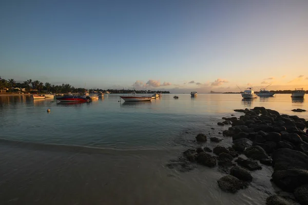 Puesta de sol en la playa de la isla de Mauricio donde los yates flotan en el agua y los barcos — Foto de Stock