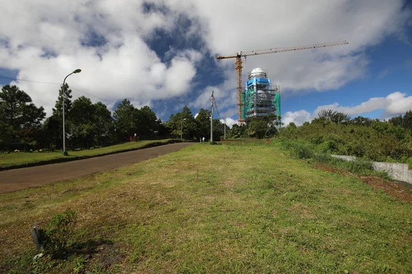 Nära skogen och vägen finns det en konstruktion av ett högt torn och en kran — Stockfoto